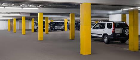 Un estacionamiento de varios niveles con pilares amarillos y varios vehículos estacionados.