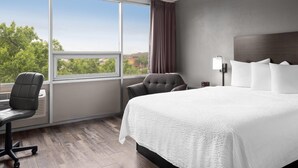 A hotel room with a large window, a bed, a chair, and a desk. - Baymont by Wyndham Great Falls City Center (Great Falls)
