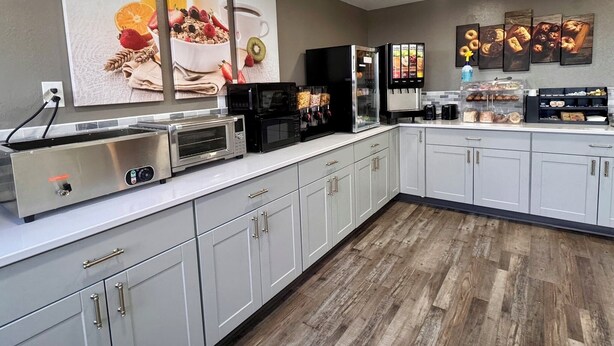 A modern kitchen with a built-in toaster, microwave, and coffee maker, along with a refrigerator and a coffee dispenser. - Baymont by Wyndham Great Falls City Center (Great Falls)