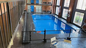 Una piscina interior con barrera de vidrio, cerramiento seguro y una mesa con sillas.