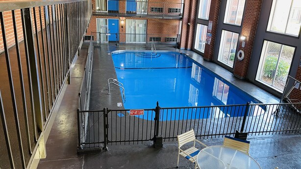 An indoor swimming pool with a glass barrier, a keep gate, and a table with chairs.