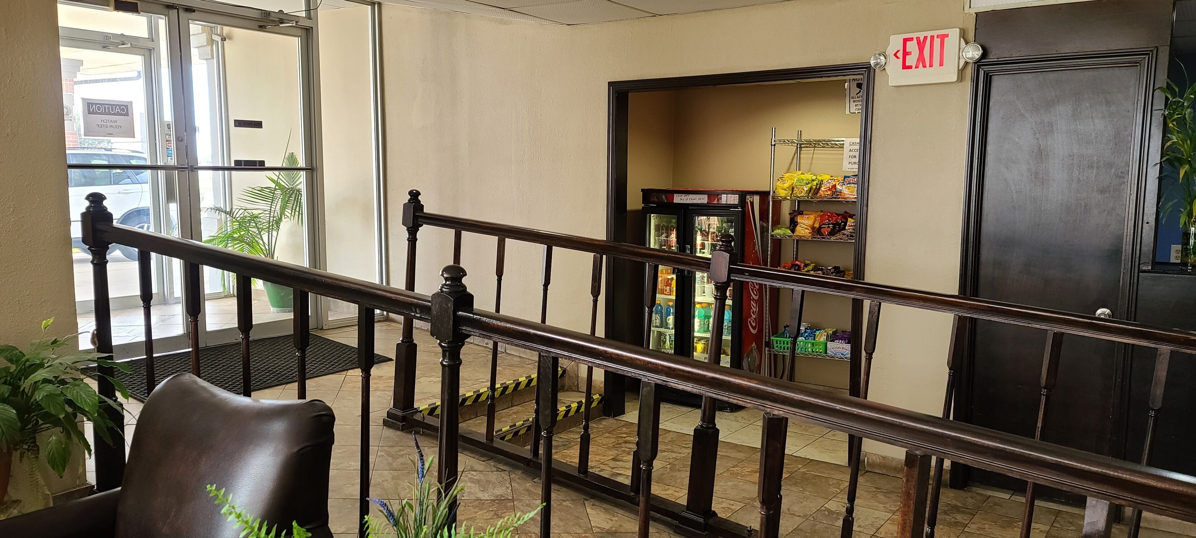 Un vestíbulo de hotel con una escalera, un refrigerador Coca-Cola y un estante con aperitivos.