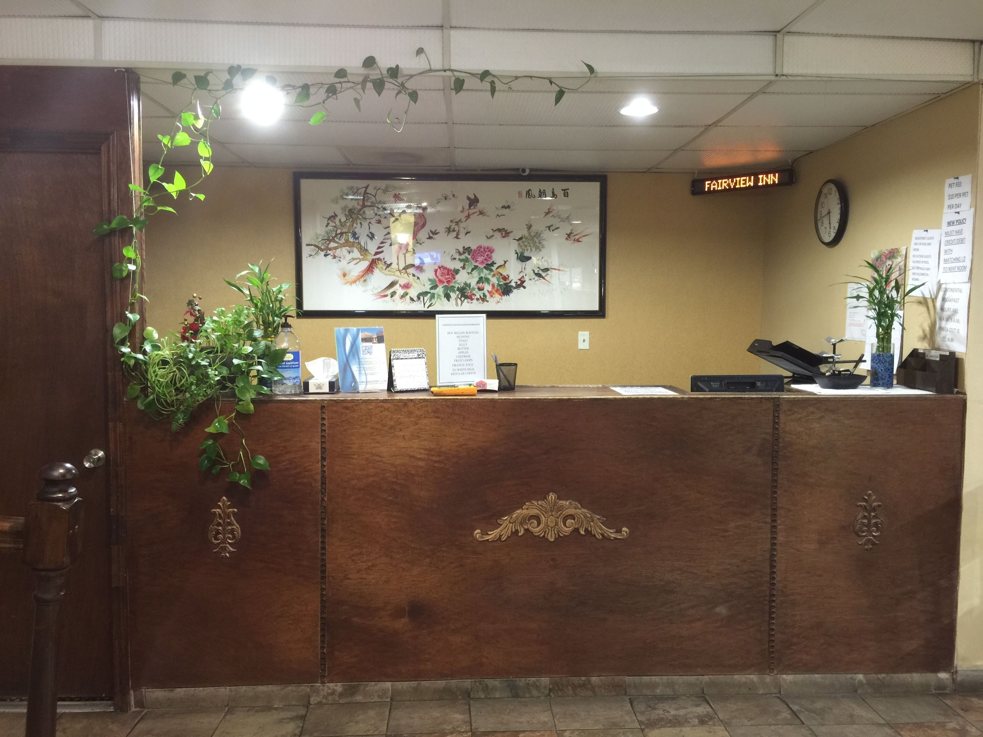 Un comptoir d’accueil avec une horloge, une œuvre d’art encadrée et une enseigne indiquant le nom « Fairview Inn ».