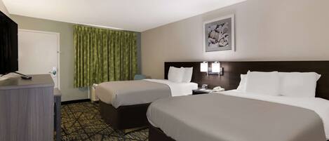 A hotel room with two beds, a desk, a telephone, and a green curtain.