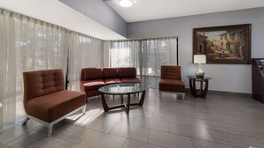 A modern living room with a glass coffee table, two sofas, and a painting on the wall.