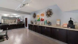 A modern kitchen with dark cabinets, a long countertop, and various appliances.