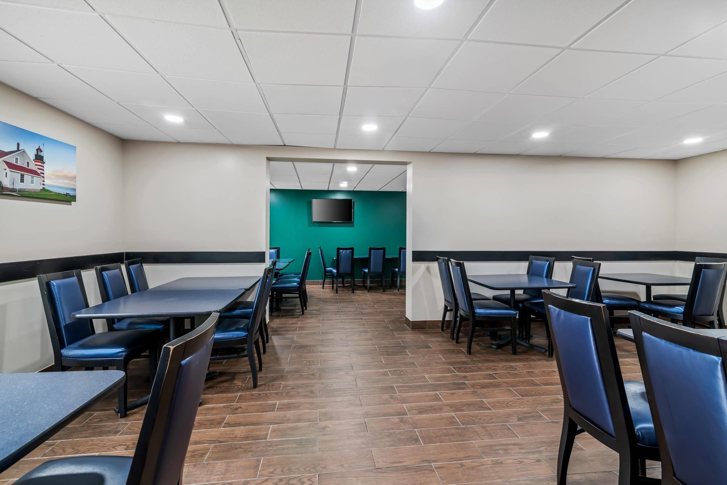 A restaurant with booths and tables, a tiled floor, and a green accent wall.