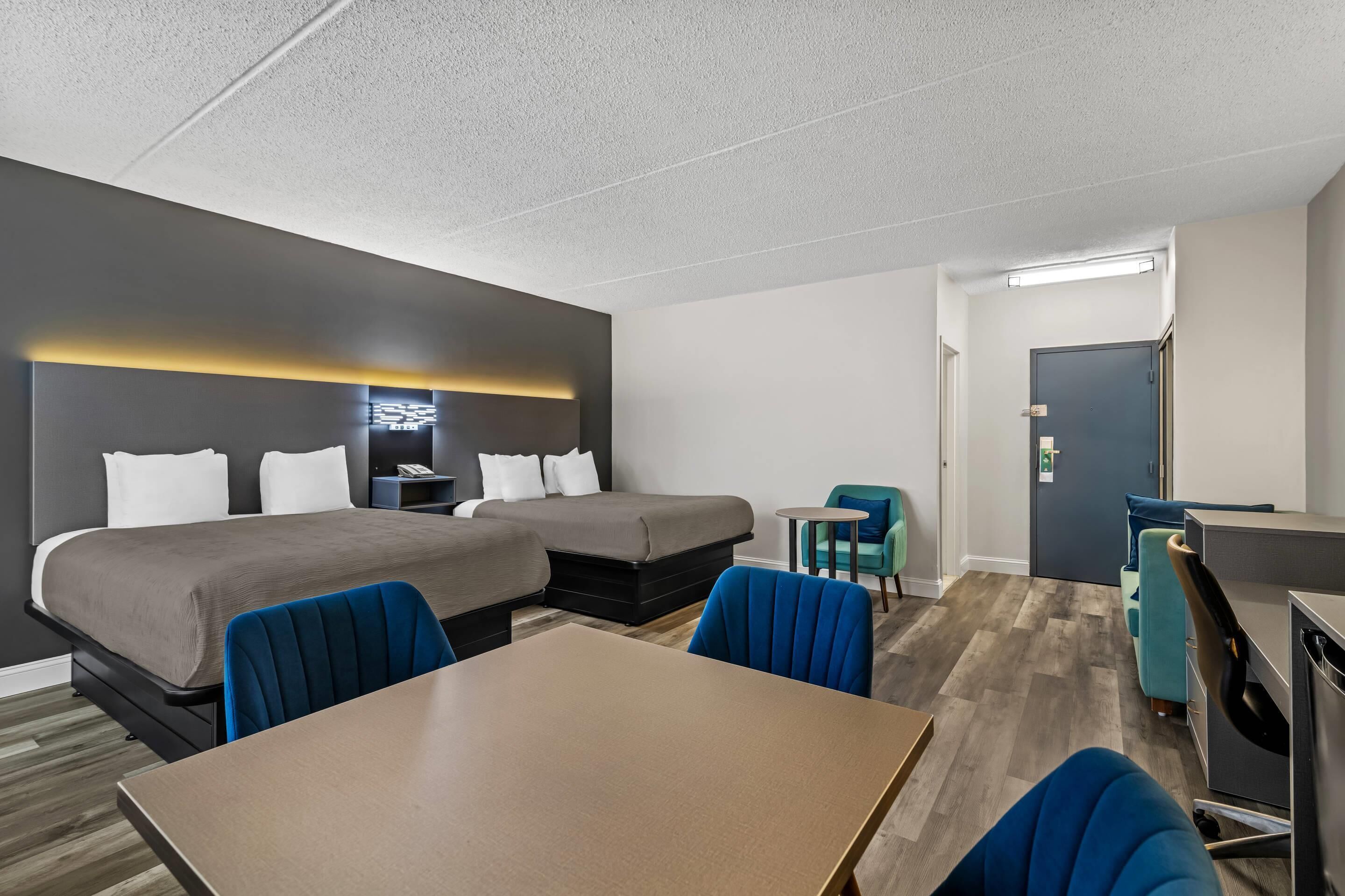 Une chambre d’hôtel avec deux lits, un bureau, une chaise et une petite table.
