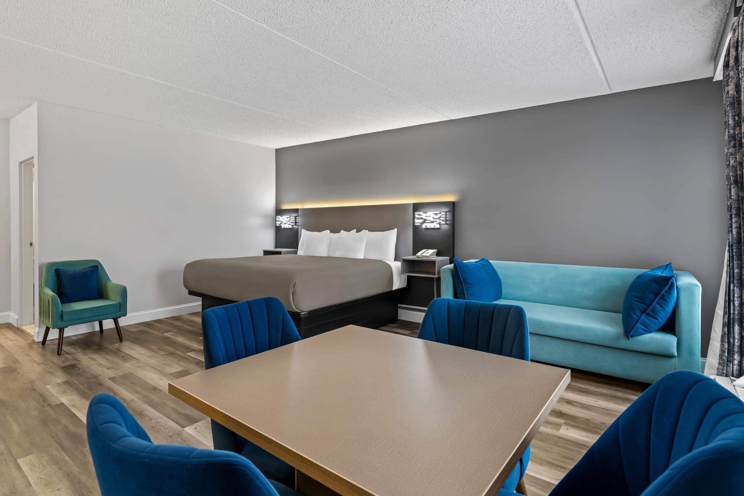 A hotel room with a bed, a sofa, a table, and two chairs.