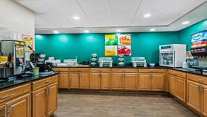 A modern kitchen with wooden cabinets, a black countertop, and various appliances including a coffee machine and a refrigerator. - Quality Inn Bangor Airport (Bangor)