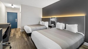 A hotel room with two beds, a desk, and a blue door. - Quality Inn Bangor Airport (Bangor)