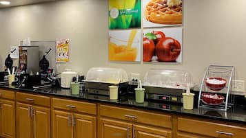 A breakfast bar with food displays, a coffee machine, and a fruit bowl.