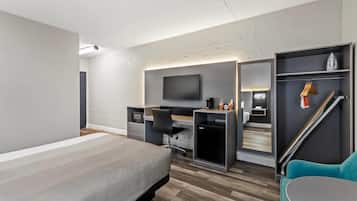 Una habitación de hotel moderna con cama, escritorio, silla y televisor.