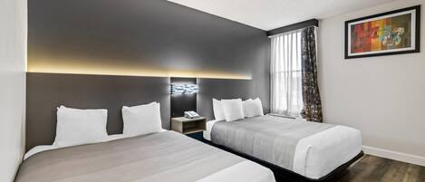 Une chambre d’hôtel avec deux lits, une table de chevet, une lampe fixée au mur et un tableau.