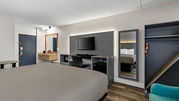 Et moderne hotelværelse med en stor seng, et skrivebord, et fjernsyn og et spejl.