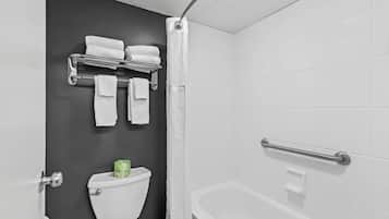 A bathroom with a toilet, a bathtub, a shower curtain, and a towel rack with folded towels.