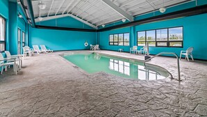 An indoor swimming pool with clear blue walls and a stone floor, surrounded by white lounge chairs. - Quality Inn Bangor Airport (Bangor)
