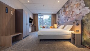Una habitación de hotel con cama, un banco, un escritorio y un ventanal grande.