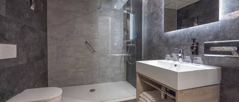 A modern bathroom with a shower, toilet, and vanity.