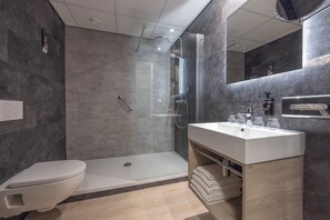 A modern bathroom with a shower, toilet, and vanity. - Fletcher Parkhotel Val Monte (Berg en Dal)