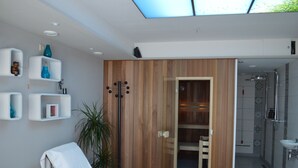 Un baño moderno con cabina de ducha de vidrio, tocador de madera y lavamanos blanco.