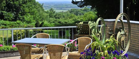 Eine Terrassengruppe mit Korbmöbeln, einem Tisch und Kübelpflanzen.