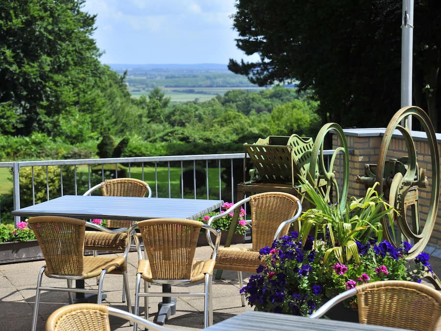 An outdoor patio with wicker furniture, a table, and potted plants.