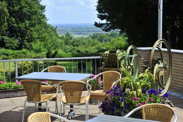 An outdoor patio with wicker furniture, a table, and potted plants.