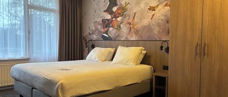 A bedroom with a large bed, a wardrobe, and a wall mural.