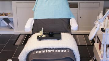 Experience a serene massage therapy room with a massage table, footrest, and amenities for a rejuvenating treatment.