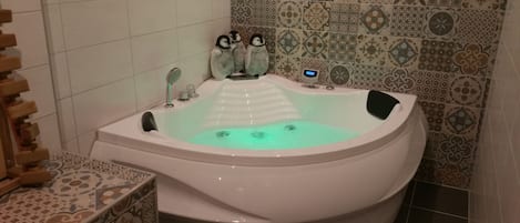 Un baño moderno con una bañera independiente, una mesita de madera y azulejos estampados en las paredes.
