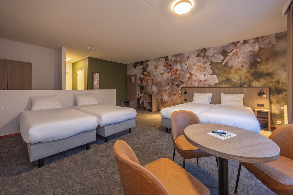 Ein Hotelzimmer mit zwei Betten, einem kleinen Tisch und einem Sofa.