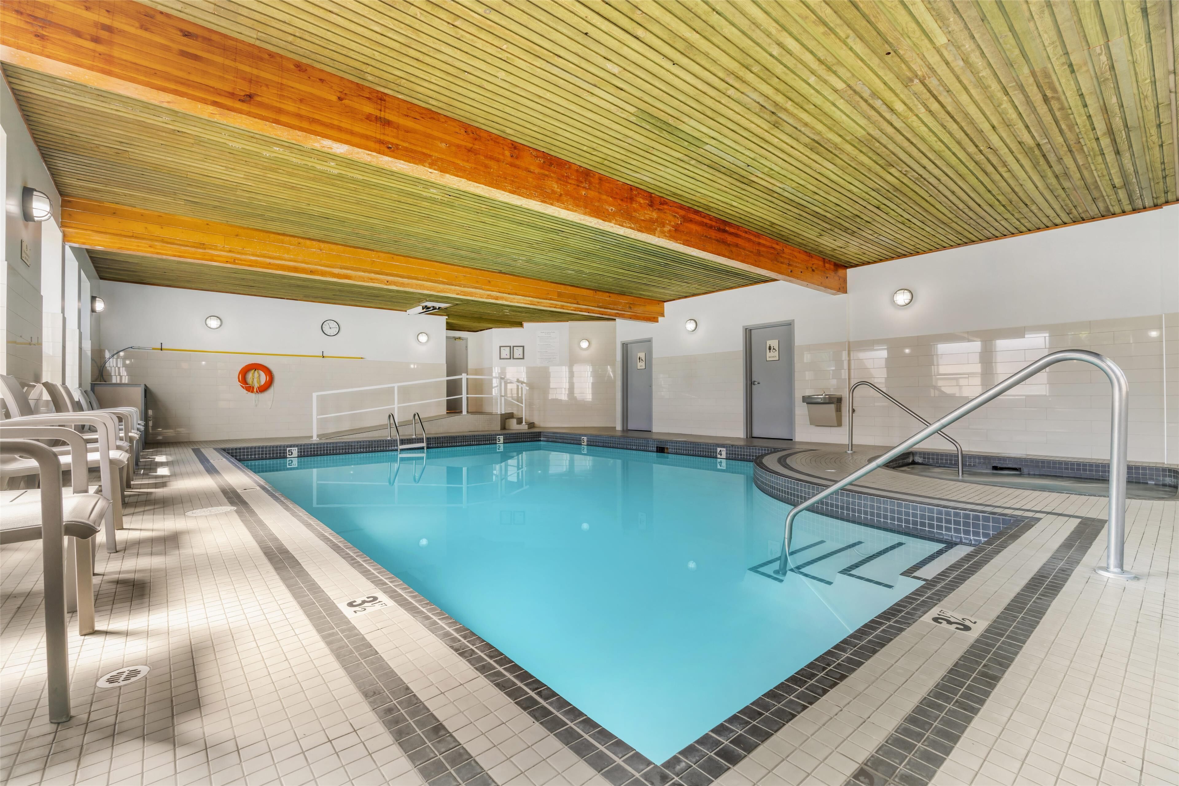 Una piscina interior con carriles claramente delimitados, techo de madera y paredes de azulejos.