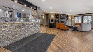 A modern interior with a stone accent wall, wooden flooring, and contemporary furniture. - Best Western Plus Country Meadows Inn (Langley)