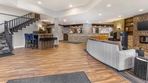 A spacious living area with a wooden floor, a staircase, a bar area, and a seating area with a sofa and chairs. - Best Western Plus Country Meadows Inn (Langley)