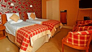 A hotel room with two beds, a wardrobe, a television, and a chair.