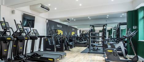 Une salle de sport équipée de tapis de course, de vélos elliptiques et de matériel de musculation.