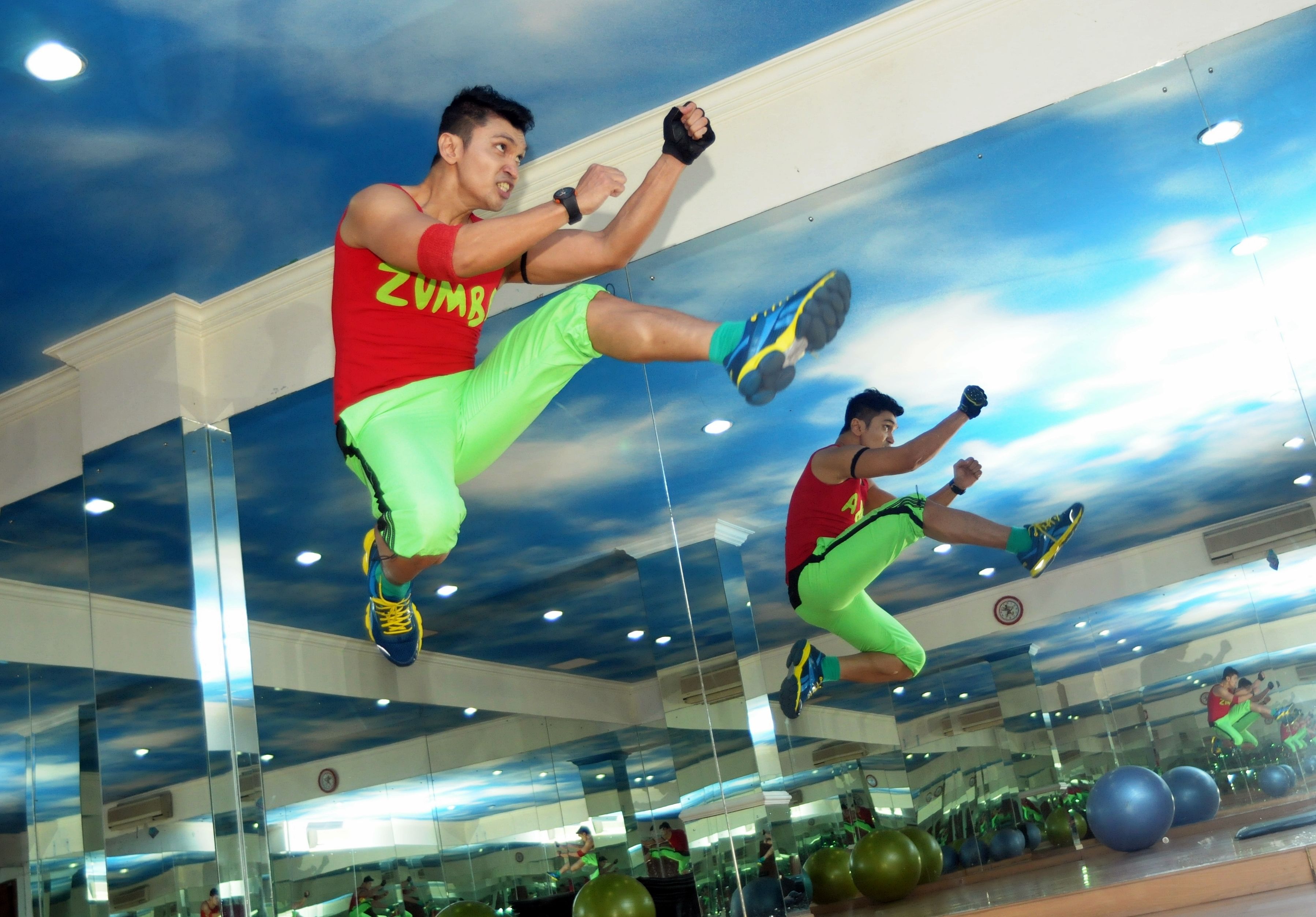 Un gimnasio con paredes de espejo, equipamiento de ejercicio y un techo con diseño de nubes.