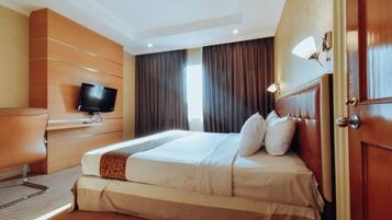 Une chambre d’hôtel avec un lit, une télévision, un bureau et une porte.
