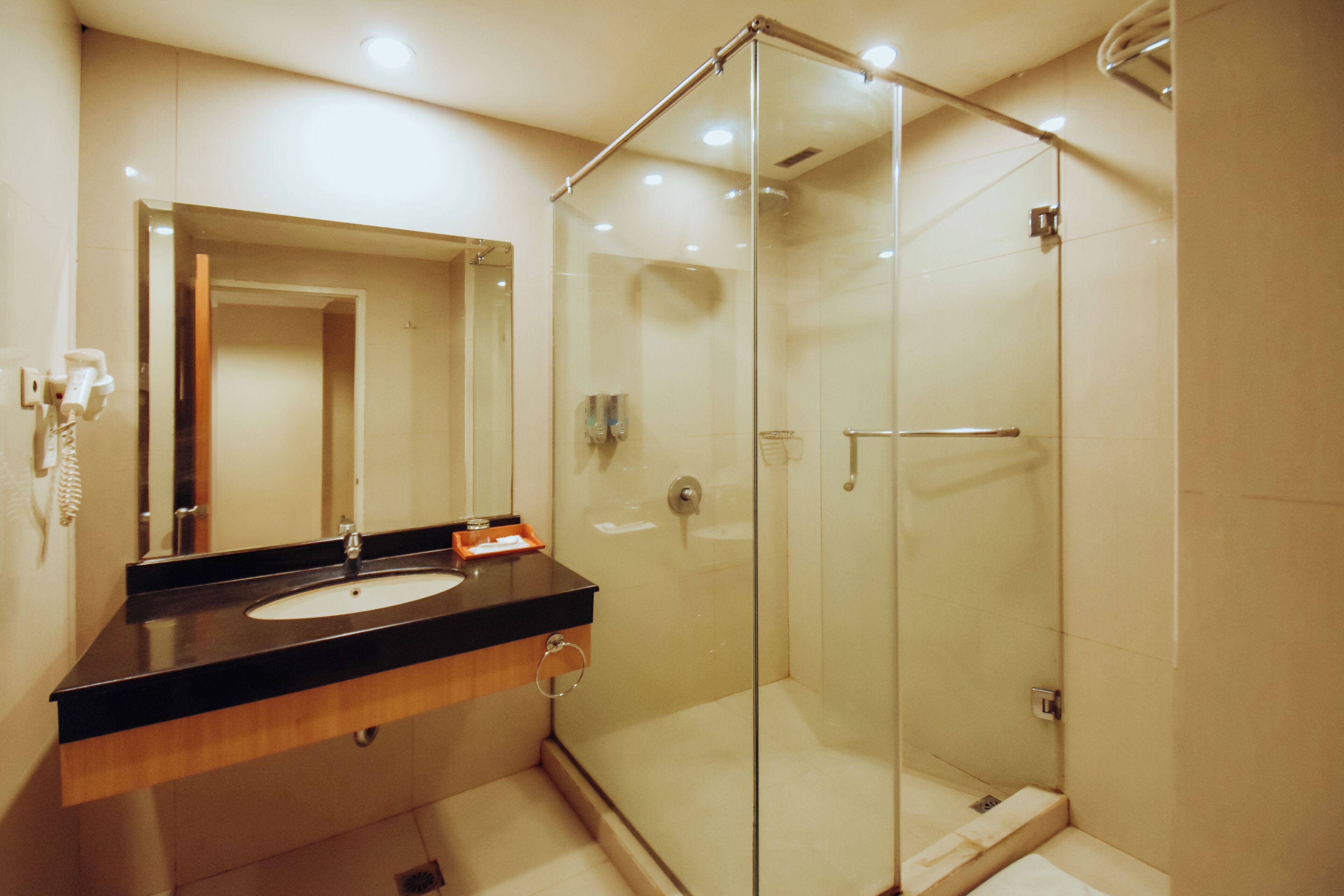 Une salle de bain moderne avec une douche à parois de verre, un lavabo sur un plan de toilette noir et un miroir au-dessus du lavabo.