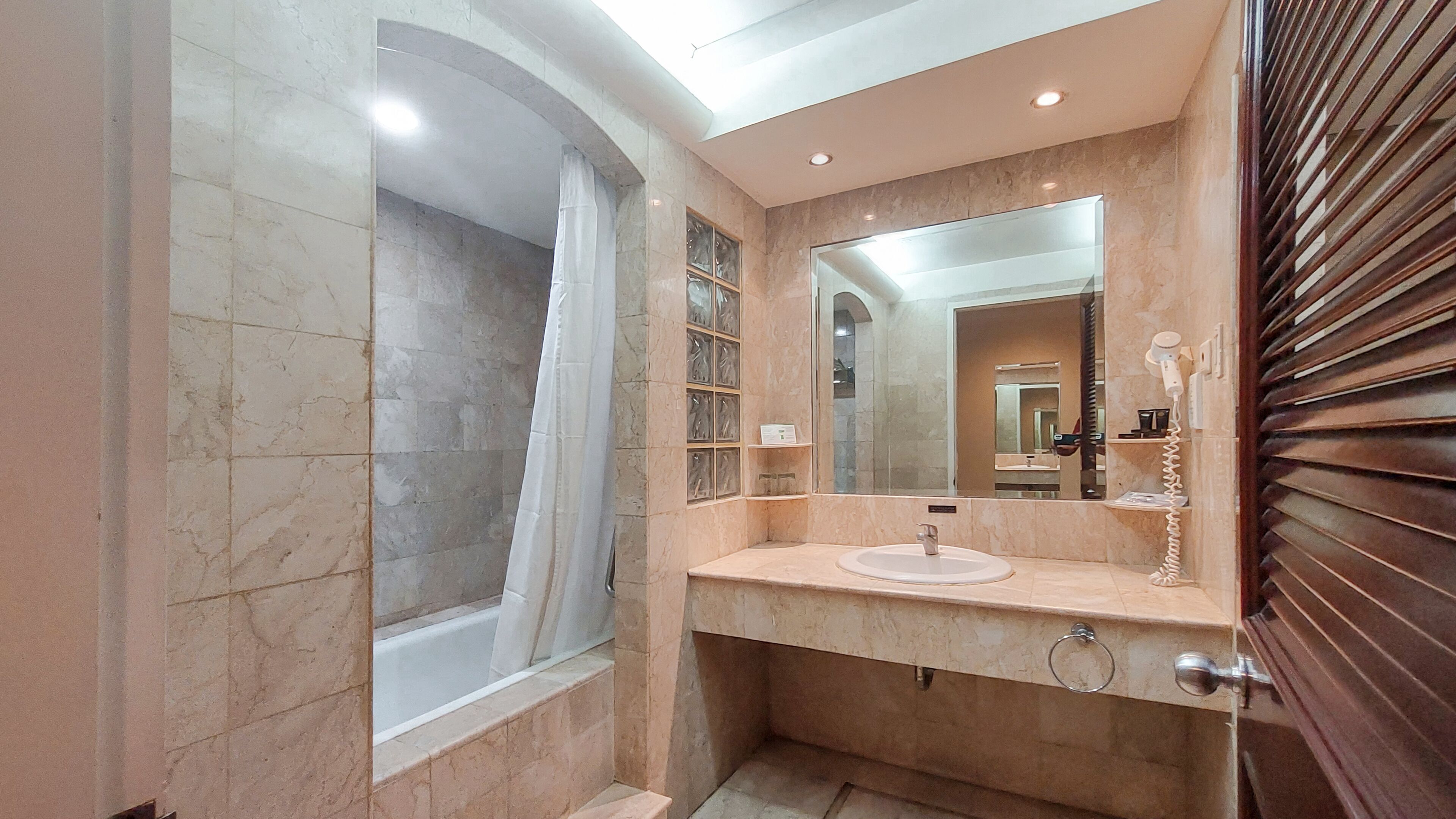 A bathroom with a marble vanity, a large mirror, and a shower area.