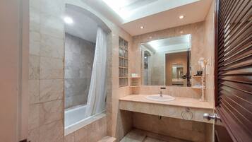 A bathroom with a marble vanity, a large mirror, and a shower area.