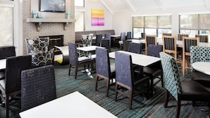 A restaurant with a brick fireplace, modern chairs, and large windows. - Residence Inn by Marriott Orlando Altamonte Springs/Maitland (Altamonte Springs)