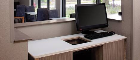 Un escritorio moderno con una computadora, teclado y un cajón pequeño.
