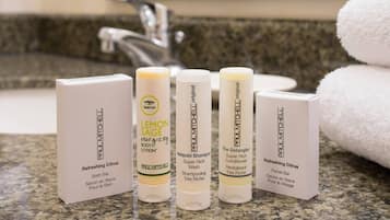 Een badkamermeubel met diverse Paul Mitchell producten, waaronder een Bath Bar, Lemon Sage body lotion, Awapuh Shampoo en The Detangler conditioner.