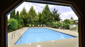 A swimming pool with lounge chairs and a view of trees. - Best Western Cowichan Valley Inn (Duncan)