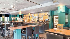 A modern bar area with multiple seating options, including bar stools and tables, and a well-stocked bar counter. - Best Western Cowichan Valley Inn (Duncan)