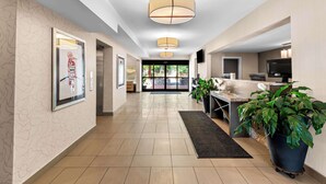 A modern hotel lobby with a long corridor, large pendant lights, a reception desk, and potted plants. - Best Western Cowichan Valley Inn (Duncan)