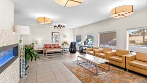 A modern living room with a flat-screen TV, leather sofas, a coffee table, and a large window offering a view of the outdoors. - Best Western Cowichan Valley Inn (Duncan)