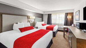 A hotel room with two beds, a desk, a TV, and a window with curtains. - Best Western Cowichan Valley Inn (Duncan)